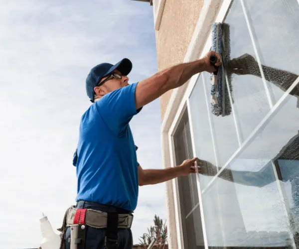 Window cleaner washing second-story windows in Cheney, WA